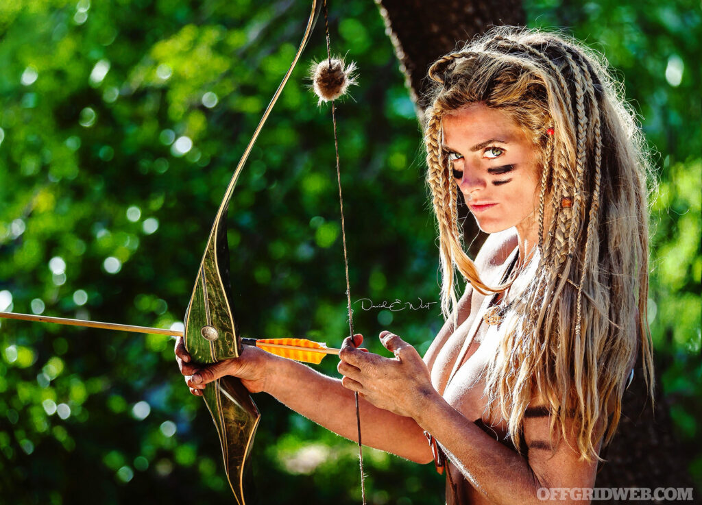 Photo de la concurrente de Naked and Afraid Melissa Miller tenant un arc primitif.