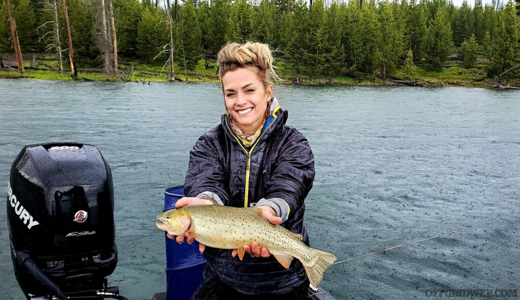 Photo de Melissa Miller pêchant depuis un bateau sur un lac, tenant un poisson qu'elle a attrapé.