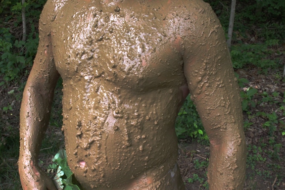 Un homme recouvert de boue pour se camoufler.