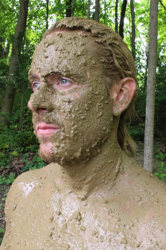 Visage d'un homme recouvert de boue pour se camoufler.