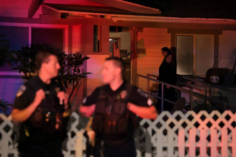 Des habitants du quartier observent la police postée au coin de la rue devant la résidence de Cole Tomas Allen, le suspect dans la fusillade survenue lors du dîner annuel de l'Association des correspondants de la Maison Blanche à Washington, D.C., à Torrance, en Californie, aux États-Unis, le 25 avril 2026. REUTERS/Daniel Cole