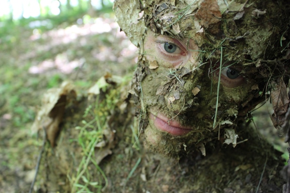 Camouflage du visage des hommes avec de la boue et des feuilles.